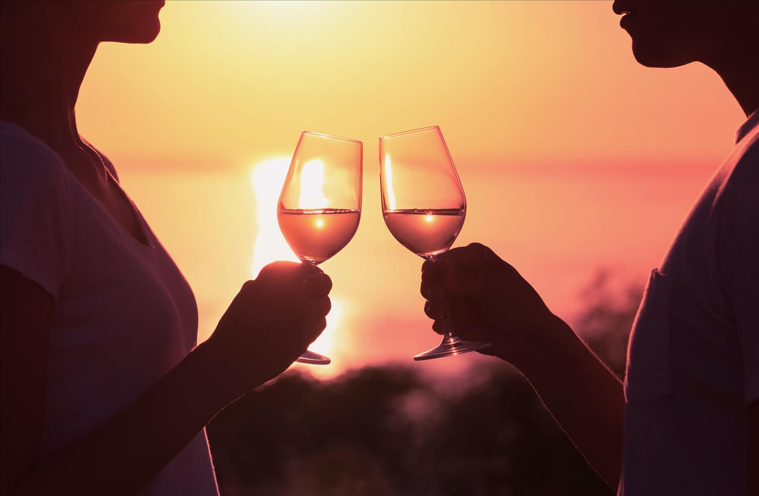 couple enjoying a romantic glass of wine as the sun sets 